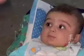 巴以冲突前线，加沙空袭幸存婴儿在巴勒斯坦记者的安抚哄逗下笑了图片