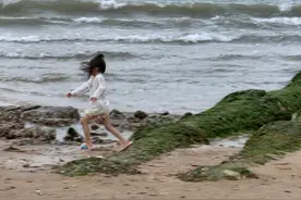 荣成爱莲湾度假区沙滩上，游客在风中游玩图片