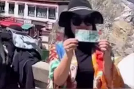 游客因争夺拍照打卡点大打出手，旁边一位女士趁对方“酣战”时，迅速拿出50元人民币找好角度拍了一张。图片