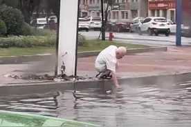 青岛暴雨路面下水道堵塞，白发老人徒手疏通，目击者：他爱干净却愿意掏垃圾图片