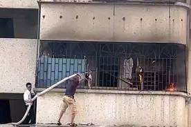 广州两人站三楼墙外帮助灭火引热议 灭火者：站的地方只有不到20厘米宽图片