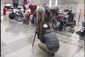 上海一小伙雨中脱下鞋子，蹲着帮赤脚流浪老人穿上，救助站：老人不愿接受救助管理图片