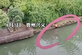 孩子公园里落水，女环卫工扶着岸边石头试探下水，脚踩水底挪步，成功抓住孩子将其托举上岸图片