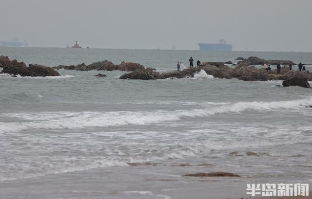 沿海迎大浪，游客沙滩驻足