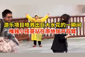 游乐项目喷溅出巨大水花的一瞬间，小孩哥站在原地张开双臂图片