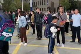 年轻爸妈带娃现状，男子吃着辣条在校门口等娃，网友：在校门口吃辣条的还是那批人。图片