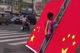 国旗被风刮倒在地上，过路小男孩下车把国旗扶正摆好。#国旗 #国庆 #少年强则国强 @抖音短视频视频封面