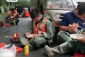 参加救援的人民子弟兵靠在车旁累到睡着，手里还捧着没吃完的盒饭图片